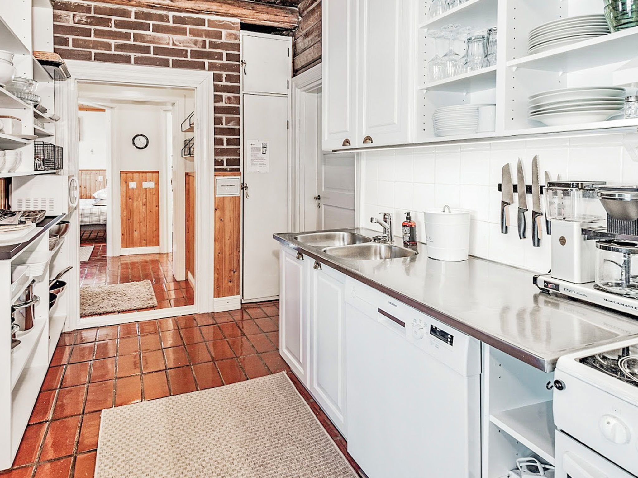 A kitchen with white cabinets, a stainless steel sink, and a coffee maker.
