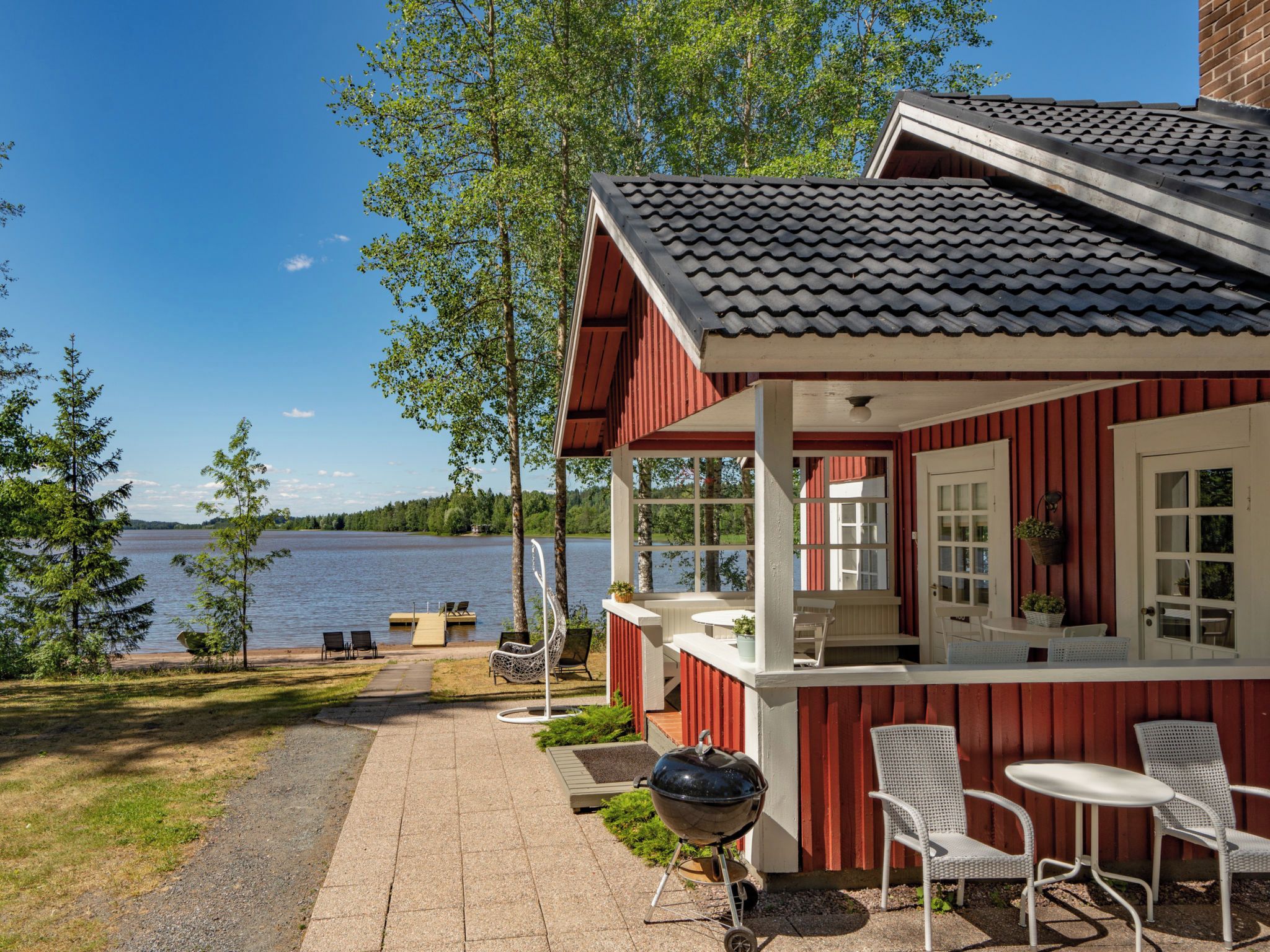 A lakeside cabin with a patio, outdoor seating, and a grill.