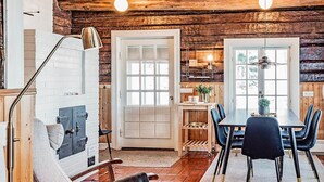 Un interior rústico con una escalera de madera, un comedor con mesa y sillas, y una cocina con un armario de madera y un colgador de techo.