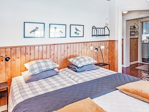 A bedroom with a wooden headboard, a bed with multiple pillows, and three framed bird pictures on the wall. - Sepelkyyhky by Interhome (Somero)