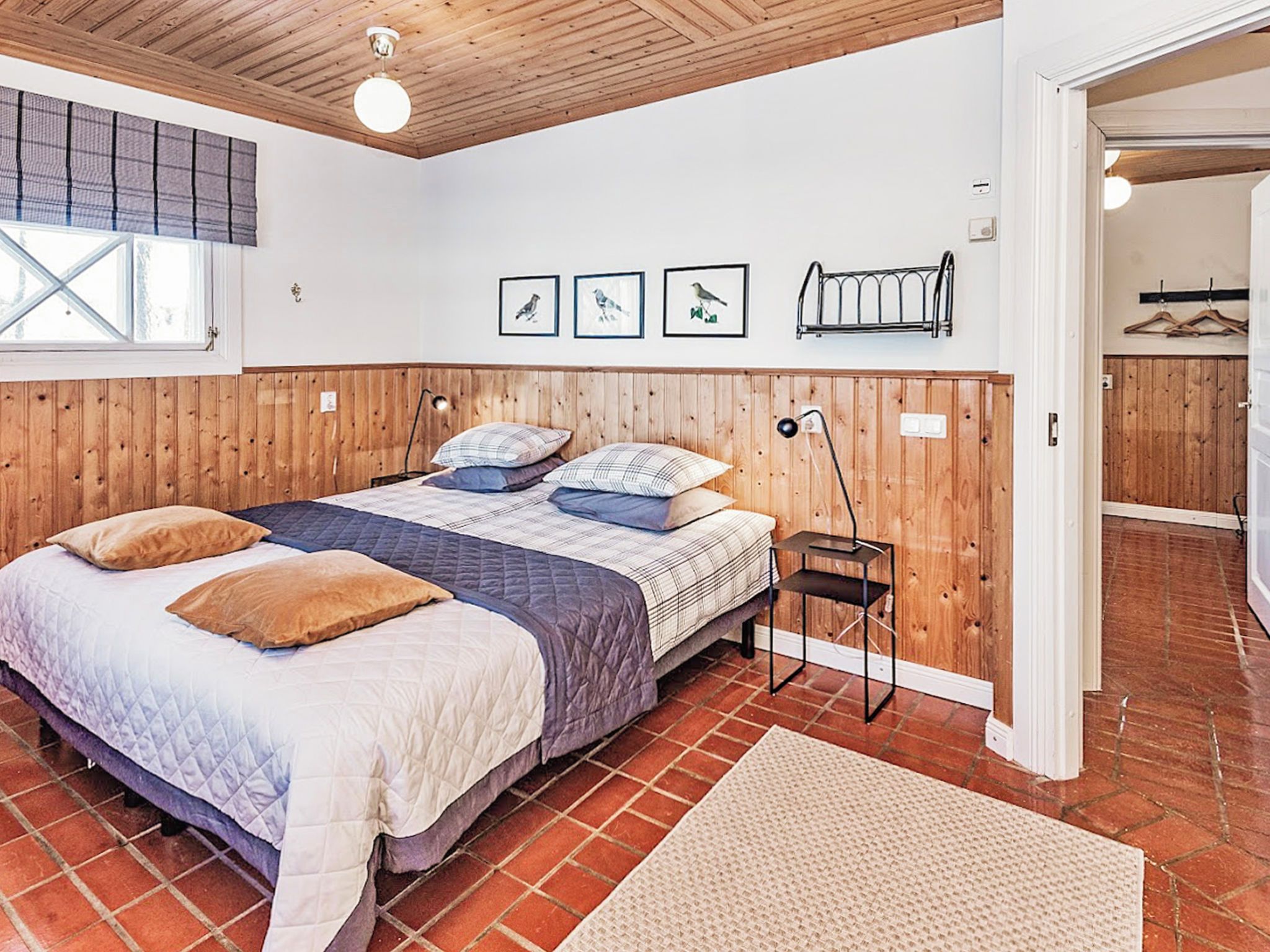 A bedroom with a wooden headboard, a bed with multiple pillows, a bedside table, and a hanging light fixture.