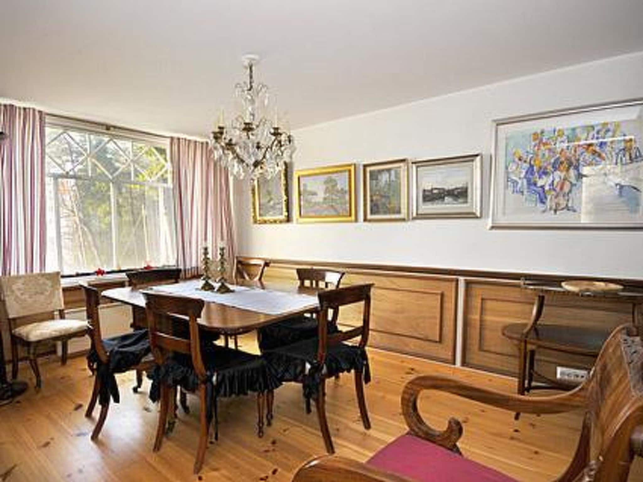 Un comedor con mobiliario de madera, una araña y cuadros en la pared.