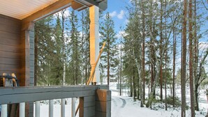 Una terraza de madera con vista a un bosque nevado.