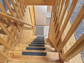 Eine Holztreppe mit schwarzen Sprossen, die zu einer Tür führt.