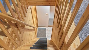 Una escalera de madera con peldaños negros que lleva a una puerta.