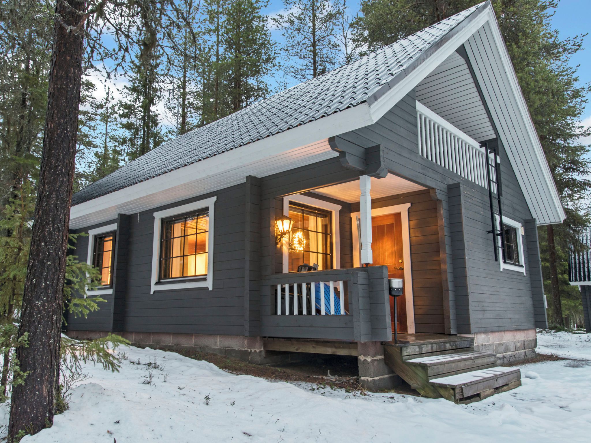Een chalet met een veranda, een voordeur en een raam.