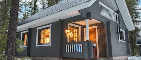A cabin with a porch, a front door, and a window.