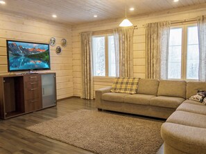 A living room with a flat-screen TV, a sofa, a coffee table, and a rug. - Villa sofia by Interhome (Sotkamo)