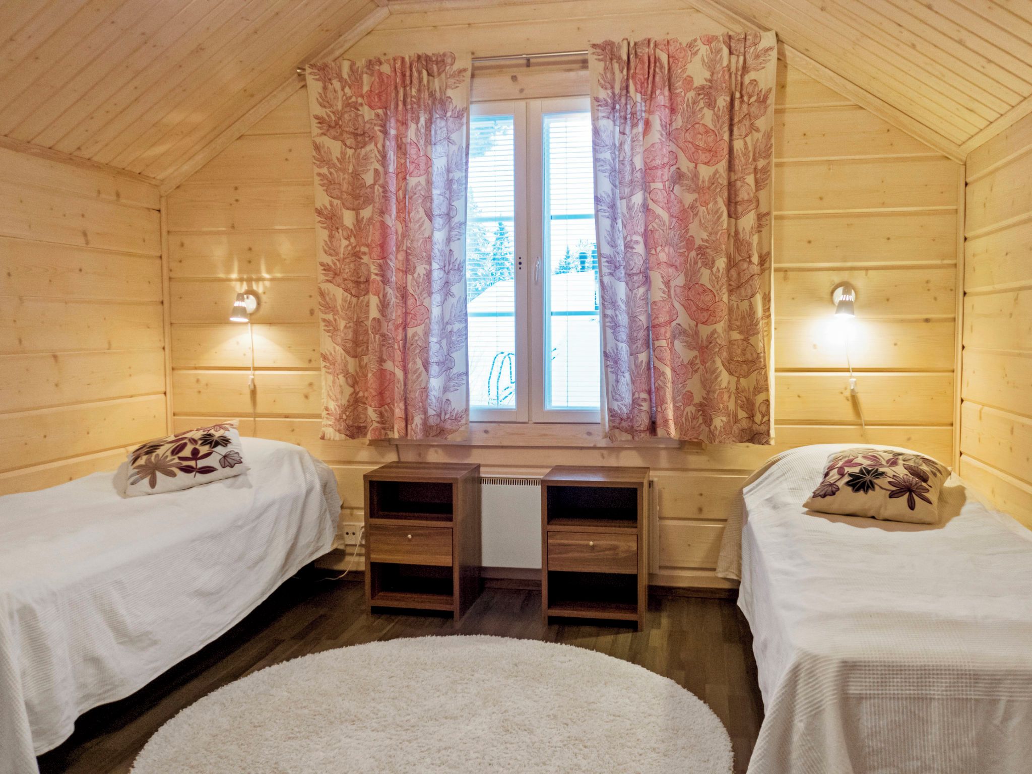 Una habitación con dos camas, un escritorio y una ventana con cortinas.