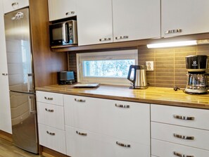 Une cuisine moderne dotée d’appareils électroménagers en acier inoxydable, de meubles blancs et d’une fenêtre laissant entrer la lumière naturelle.
