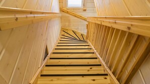 Un escalier en bois, dans un bâtiment doté d’un plafond en pente et d’une petite fenêtre en haut.
