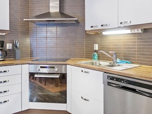 A modern kitchen with a built-in oven, a dishwasher, and a stainless steel sink. - Villa sofia by Interhome (Sotkamo)