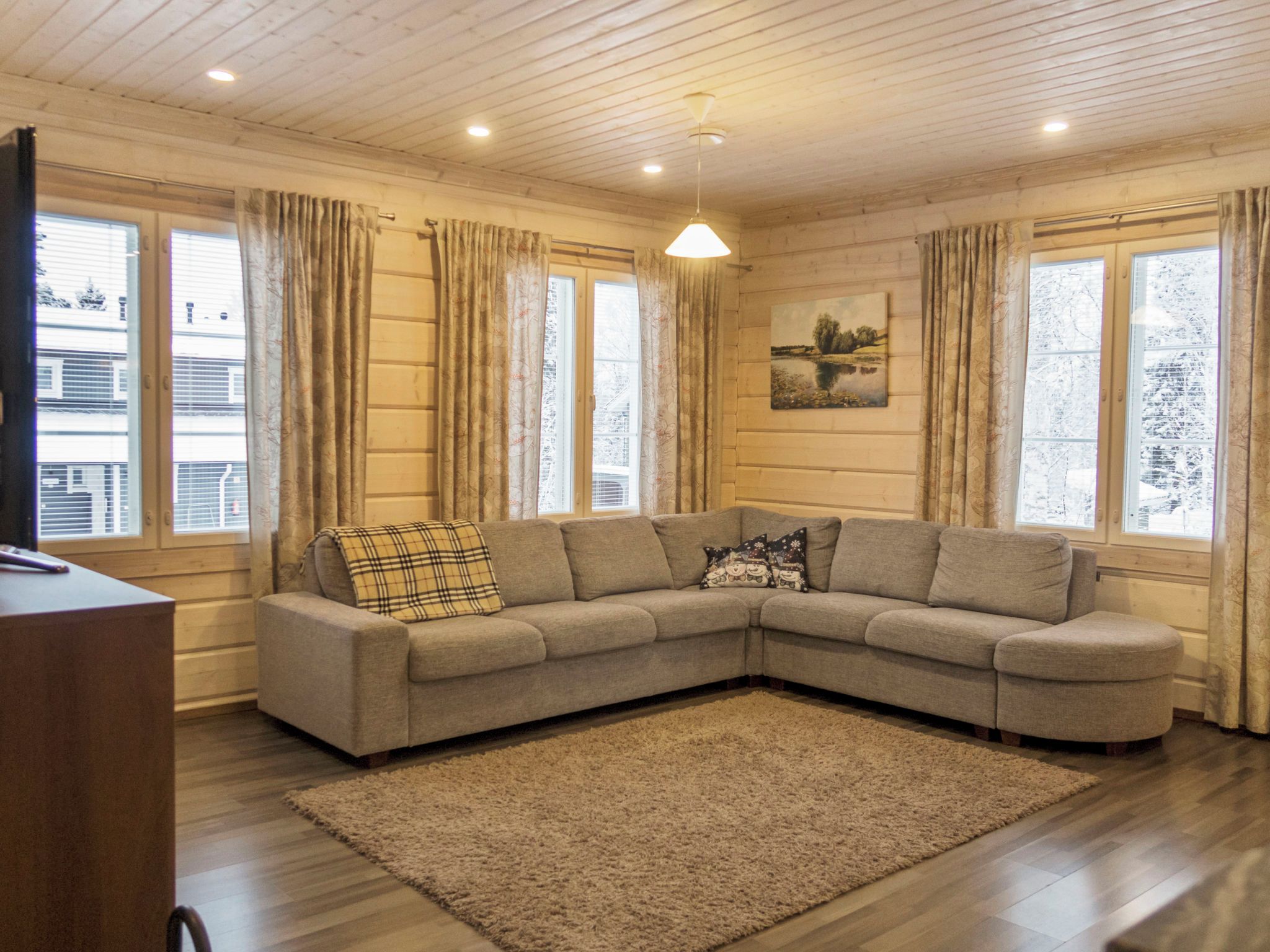 A living room with a sectional sofa, a rug, and a painting on the wall.