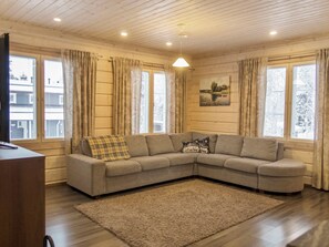 A living room with a sectional sofa, a rug, and a painting on the wall.