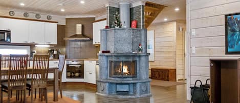 A modern interior with a stone fireplace, wooden flooring, and a kitchen area.