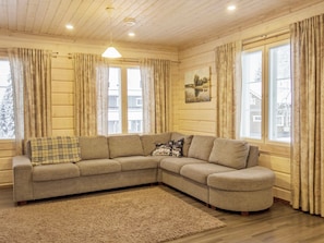 A cozy living room with a sectional sofa, a rug, and large windows with curtains. - Villa sofia by Interhome (Sotkamo)