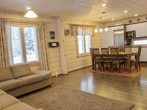 Uma sala de estar aconchegante com um sofá, uma mesa de jantar com cadeiras, piso de madeira e uma área de cozinha com micro-ondas.