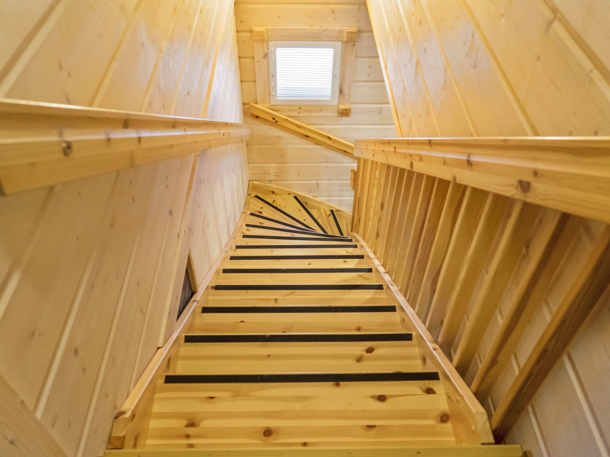 Una escalera de madera con un tragaluz en la parte superior, que conduce a un nivel superior.