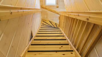 Una escalera de madera con un tragaluz en la parte superior, que conduce a un nivel superior.