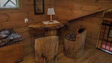 Interior acogedor de una cabaña con un banco de madera, una mesita con una lámpara y un sillón.