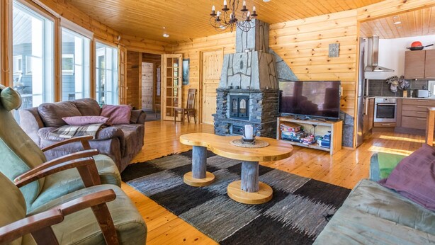 Een knus blokhutinterieur met een stenen openhaard, houten meubels en een televisietoestel.