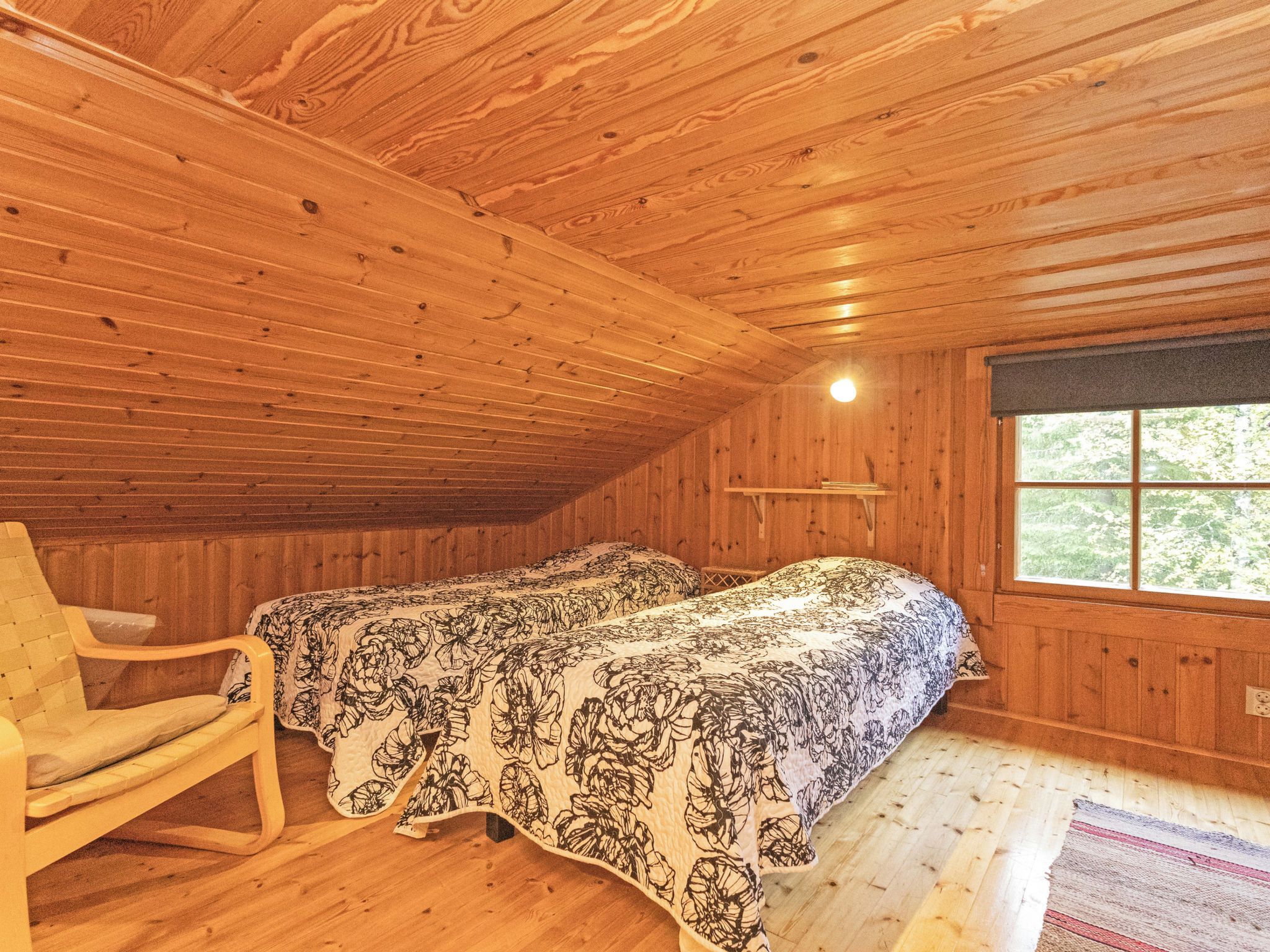 Habitació de cabana de fusta amb un llit, una cadira i una finestra.