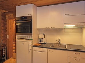 Una cocina compacta con horno integrado, microondas y cafetera.