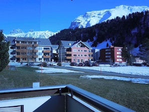 Ein Wohngebiet mit mehrstöckigen Gebäuden, ein schneebedeckter Berg im Hintergrund und ein klarer Himmel.