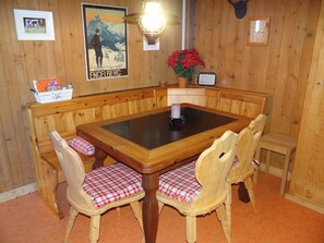 Un comedor de madera con una mesa central, bancos y sillas.