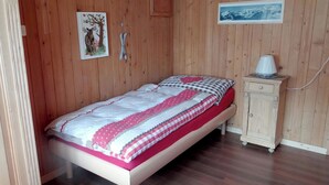 A single bed with a patterned bedspread, a small bedside table with a lamp, and a framed picture on the wall. - Steinacher 7 Appartement/Fewo 4-Bettwohnung by Interhome (Engelberg)