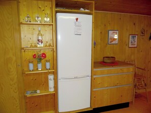 A compact kitchen with a white refrigerator, wooden cabinets, and a small countertop.
