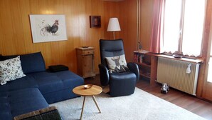 A living room with a blue sofa, a black armchair, a small wooden table, and a radiator. - Steinacher 7 Appartement/Fewo 4-Bettwohnung by Interhome (Engelberg)