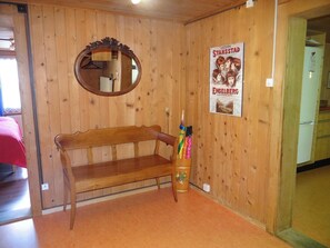 A wooden interior with a bench, a mirror, and a poster on the wall.