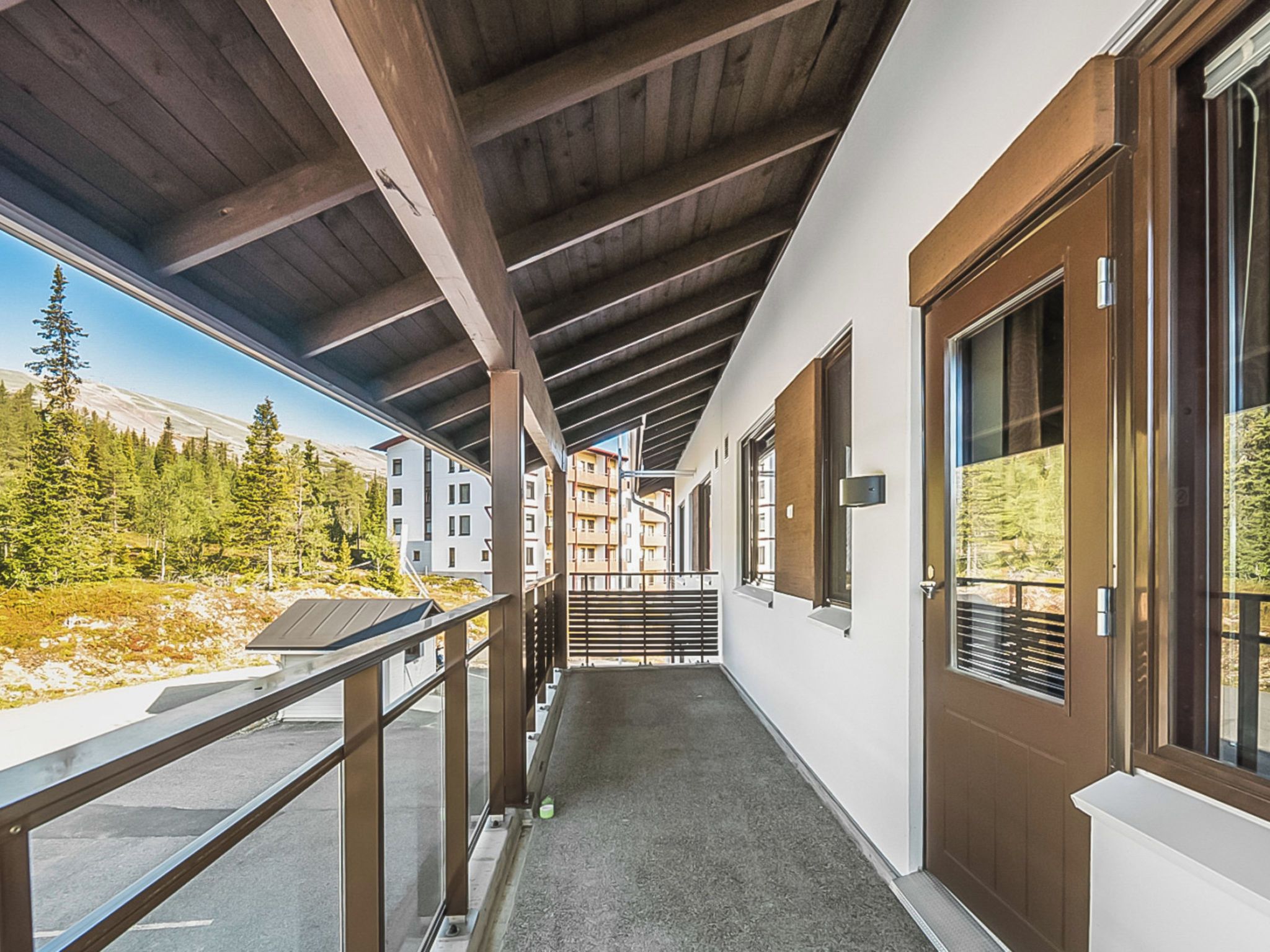 Un corridoio con soffitto in legno, una porta in vetro e vista su un paesaggio montano.