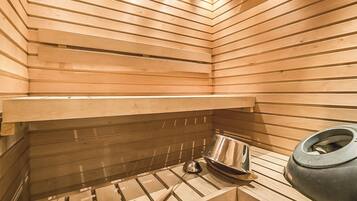 Una sauna con listelli di legno, una panca in metallo e un ampio contenitore nero.