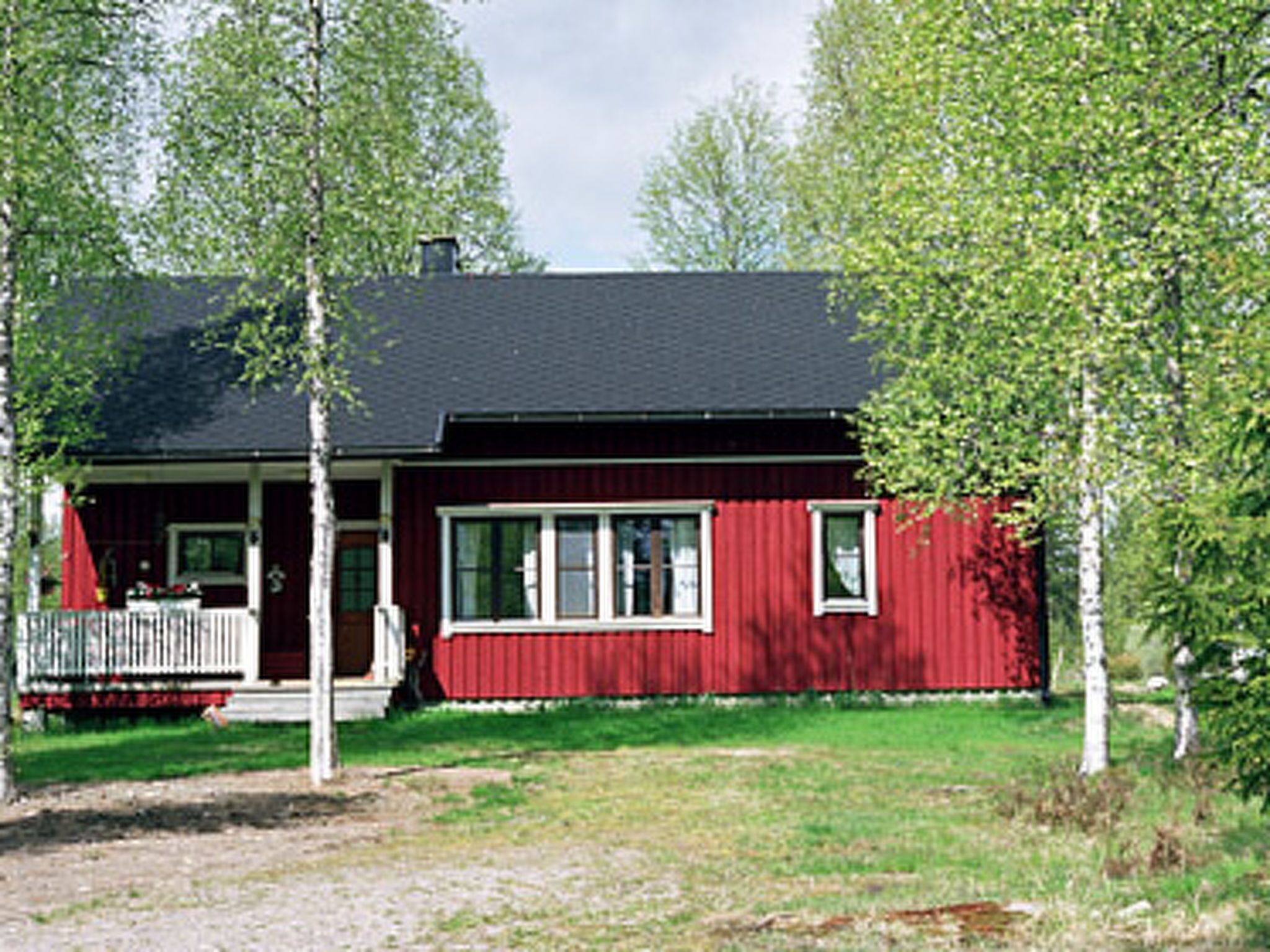 Une maison rouge avec un porche et un toit noir.