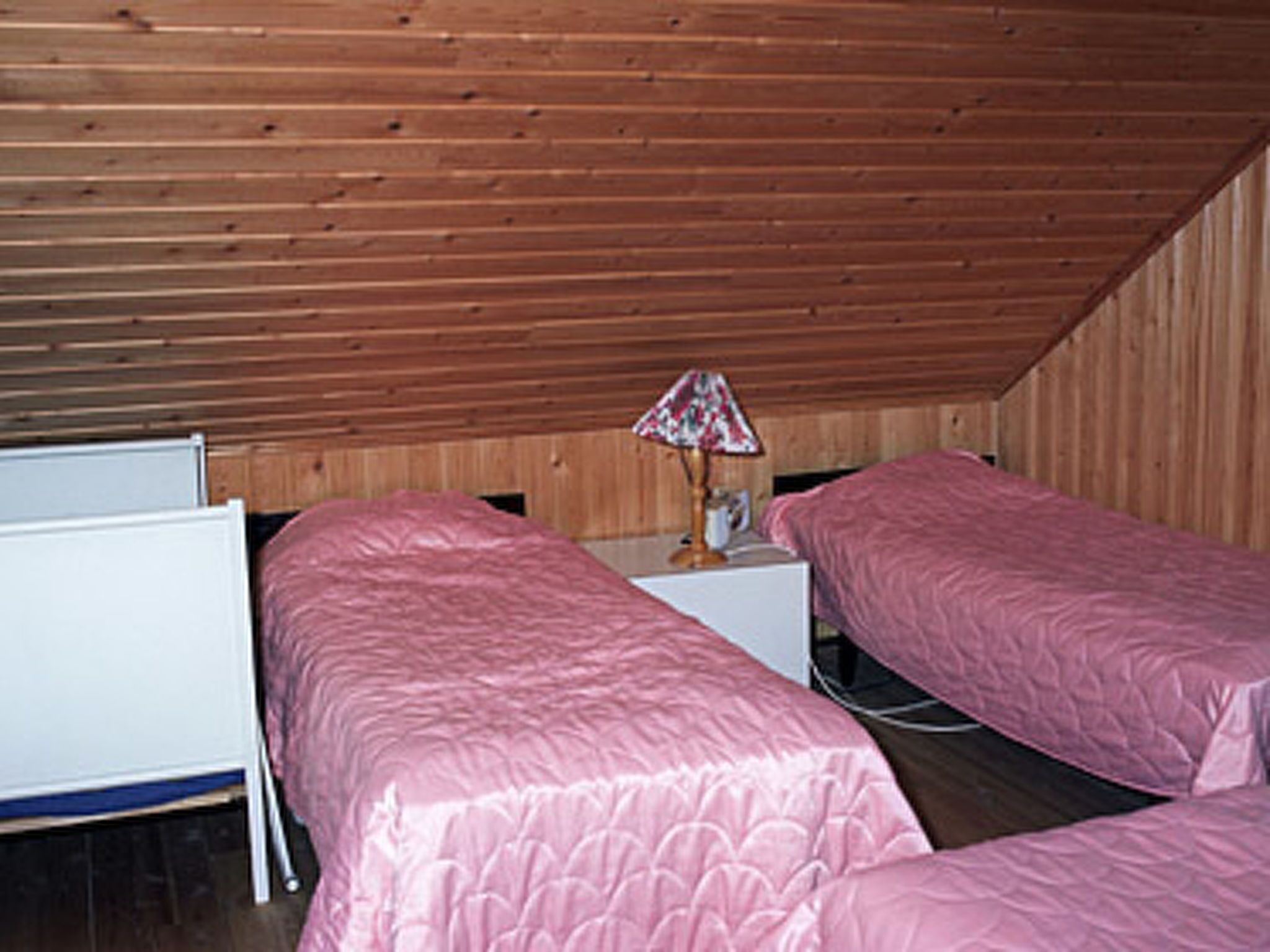 Ein Zimmer mit zwei Betten, Holzwänden, einer Tafel und einer Lampe.