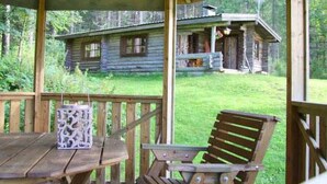 A wooden cabin with a covered porch, a table, and a chair. - Peltotupa by Interhome (Asikkala)