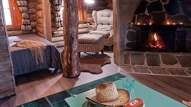 A cozy log cabin interior with a stone fireplace, a comfortable sofa, and a rustic decor. - Peltotupa by Interhome (Asikkala)