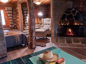 A cozy log cabin interior with a stone fireplace, a comfortable sofa, and a rustic decor. - Peltotupa by Interhome (Asikkala)