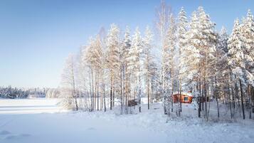 Eine Holzhütte, umgeben von schneebedeckten Bäumen in einer Winterlandschaft.