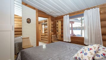 Une chambre à coucher dans un chalet en rondins, avec un lit, une chaise, une armoire en bois et une fenêtre avec des rideaux.