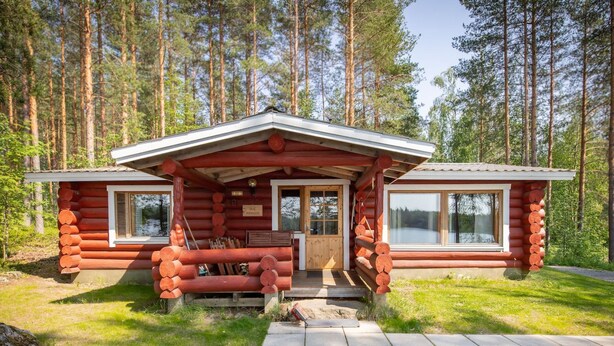 Une cabane en rondins avec un porche, un banc en bois et une porte.