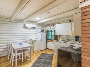 A compact kitchen with white cabinetry, a dining table with chairs, a microwave, a refrigerator, and a coffee maker. - Haaparanta by Interhome (Petäjävesi)