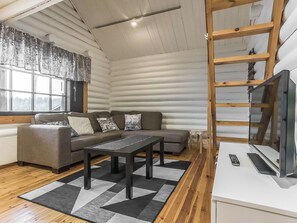 A log cabin interior with a sofa, a coffee table, a TV, and a wooden ladder. - Haaparanta by Interhome (Petäjävesi)
