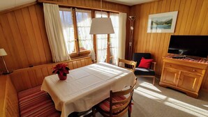 A cozy room with a dining table, chairs, a bench, a sofa, a TV, and a painting on the wall. - Bärnermutz # 2 by Interhome (Lenk)