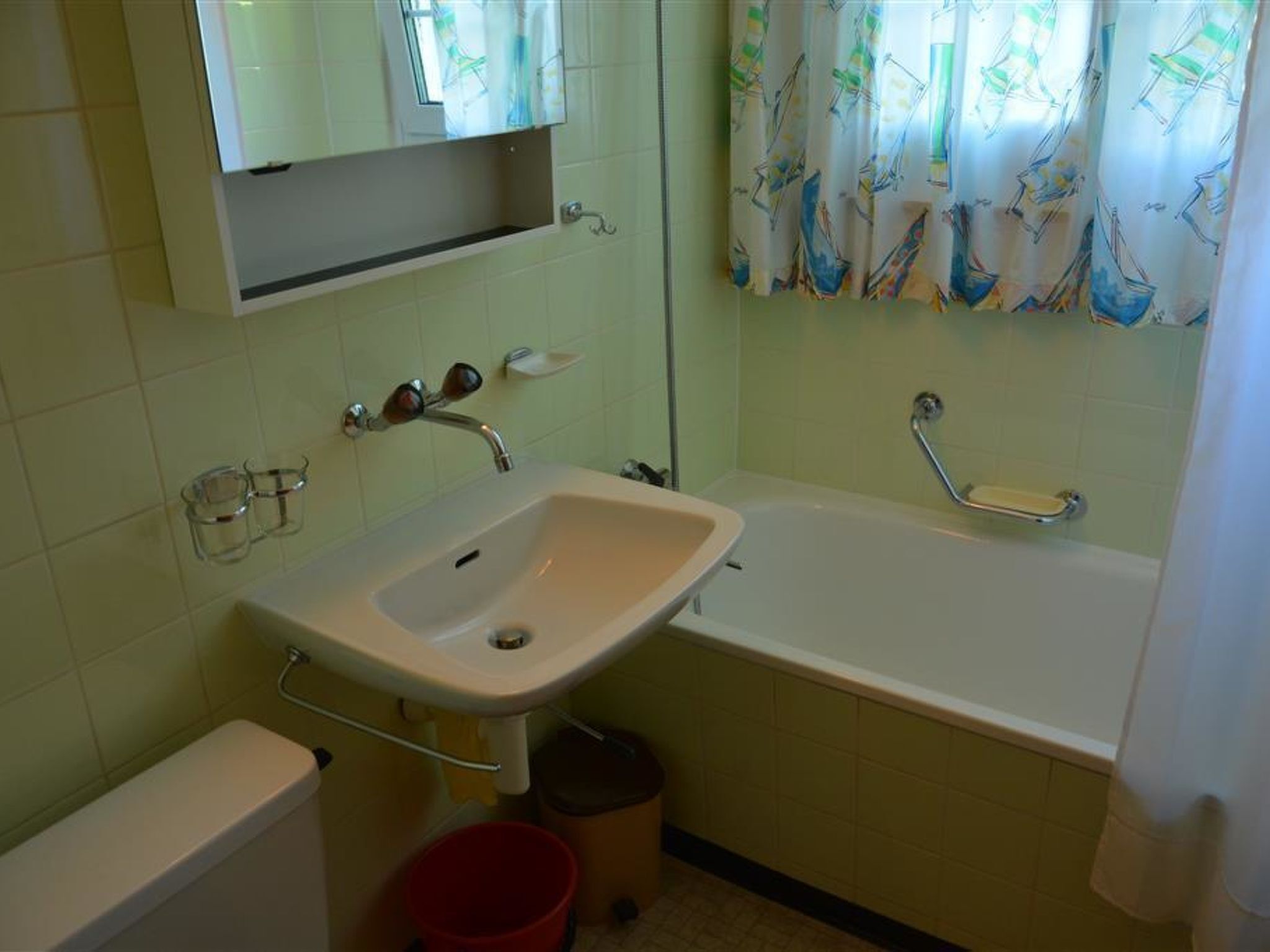 Un baño con lavamanos, espejo, bañera y cortina de ducha.
