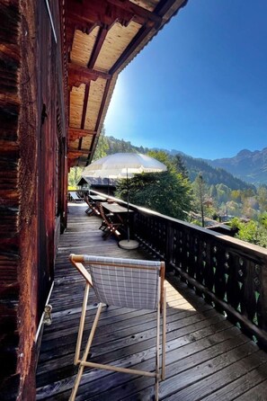 Une terrasse en bois avec une chaise, offrant une vue sur un paysage montagneux et une structure en forme de dôme blanc.