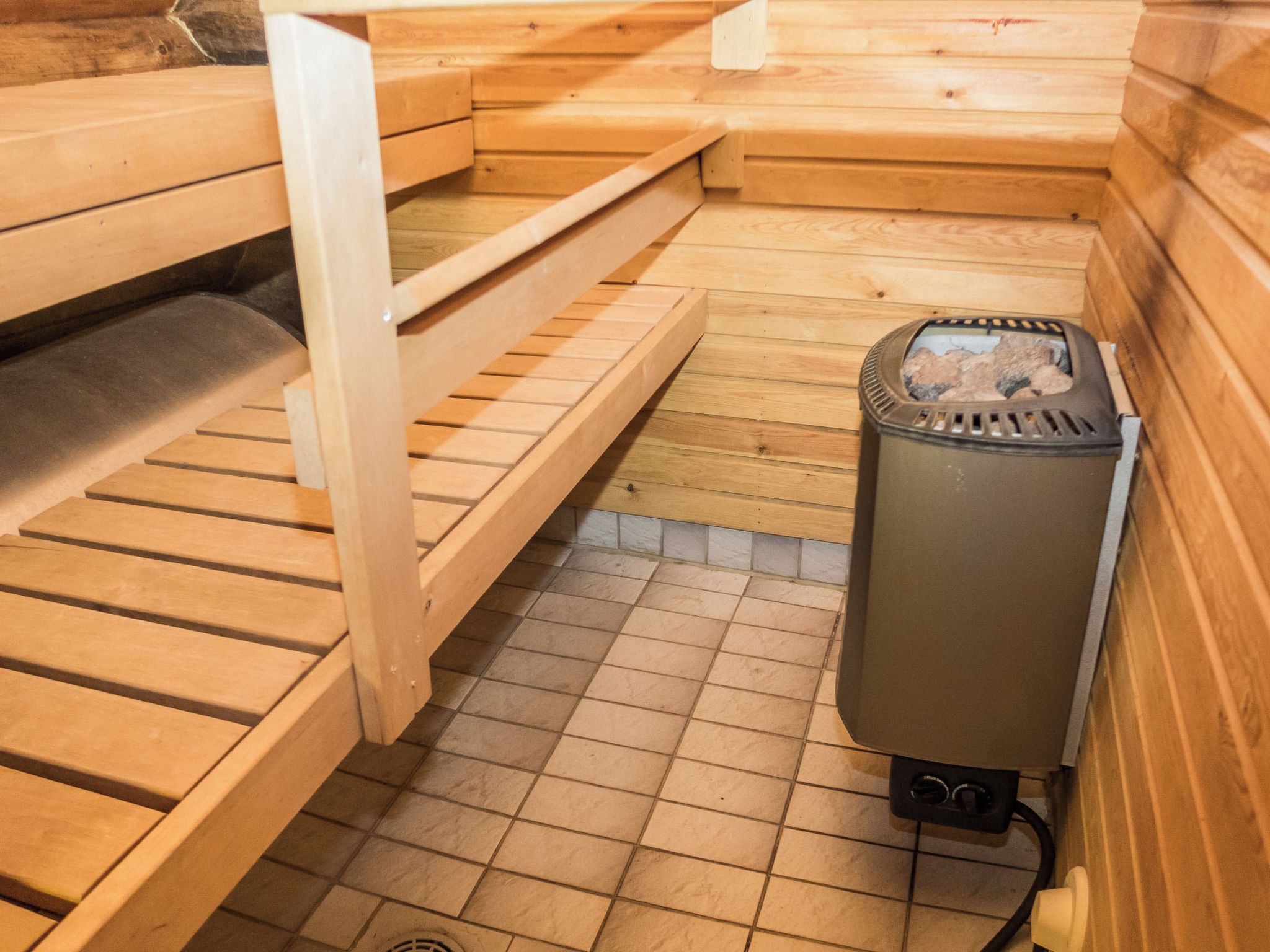 Un sauna con bancos de madera y un calentador.