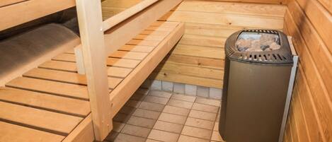Un sauna con bancos de madera y un calentador.